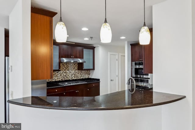 kitchen featuring decorative backsplash, a peninsula, pendant lighting, and under cabinet range hood