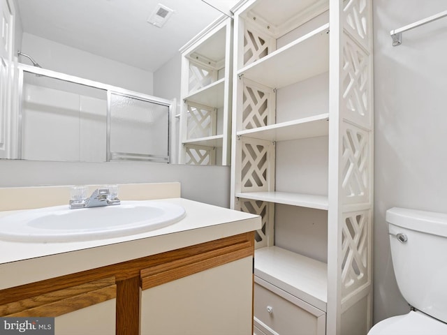 bathroom with walk in shower, vanity, and toilet