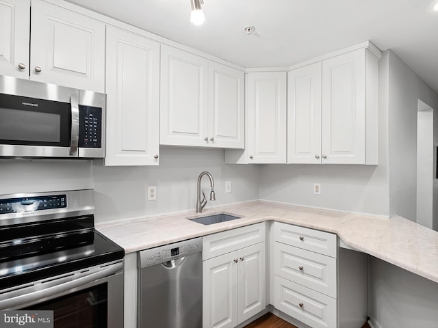 kitchen featuring appliances with stainless steel finishes, white cabinetry, sink, and dark wood-type flooring