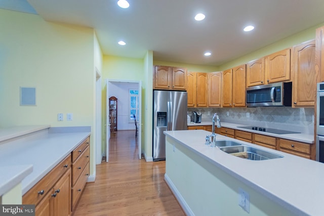 kitchen featuring appliances with stainless steel finishes, backsplash, light wood-type flooring, and sink