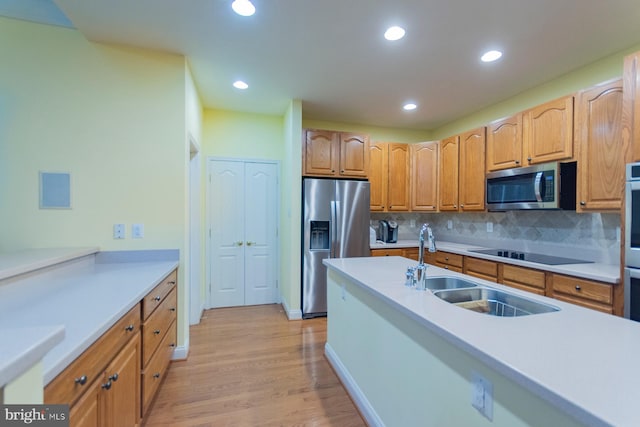 kitchen featuring appliances with stainless steel finishes, light hardwood / wood-style floors, sink, and tasteful backsplash