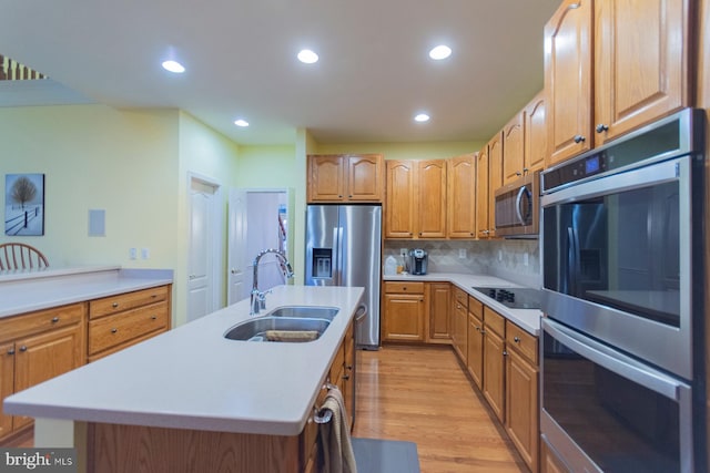 kitchen with sink, light hardwood / wood-style flooring, stainless steel appliances, backsplash, and a center island with sink