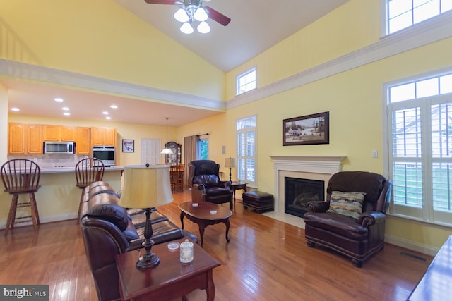 living room with high vaulted ceiling, light wood-type flooring, and ceiling fan