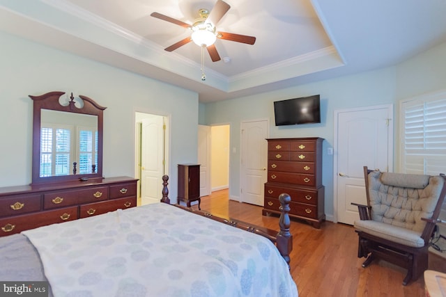 bedroom with a raised ceiling, light hardwood / wood-style floors, crown molding, and ceiling fan