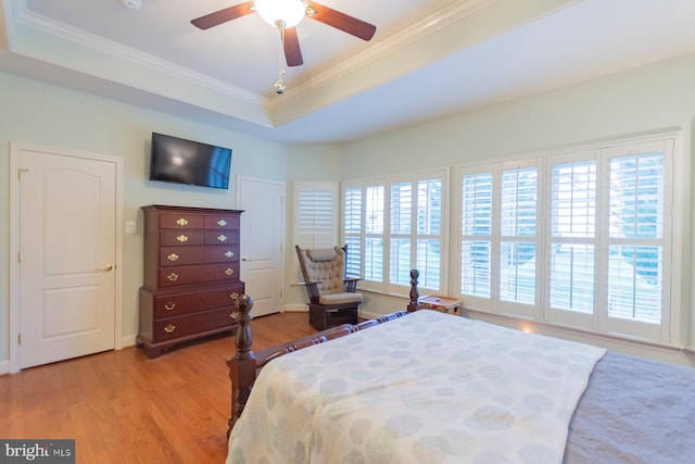 bedroom featuring light hardwood / wood-style flooring, ceiling fan, a raised ceiling, and crown molding