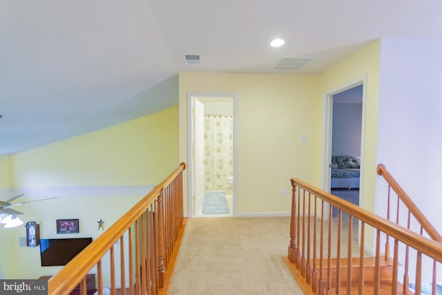 hall featuring vaulted ceiling and light colored carpet