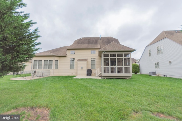 back of property with a lawn, a sunroom, and a patio