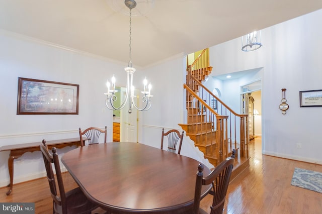 dining space with an inviting chandelier, ornamental molding, and hardwood / wood-style floors