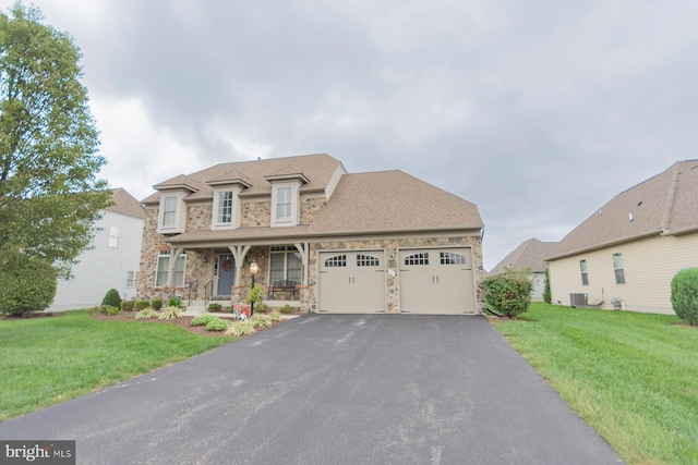 view of front of house with a garage, cooling unit, a porch, and a front lawn