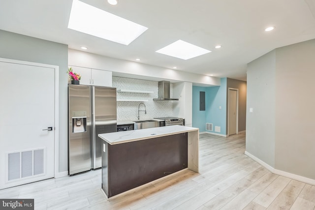 kitchen with sink, white cabinetry, light hardwood / wood-style flooring, a skylight, and appliances with stainless steel finishes