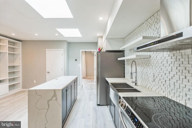 kitchen with light stone counters, appliances with stainless steel finishes, light hardwood / wood-style floors, and decorative backsplash