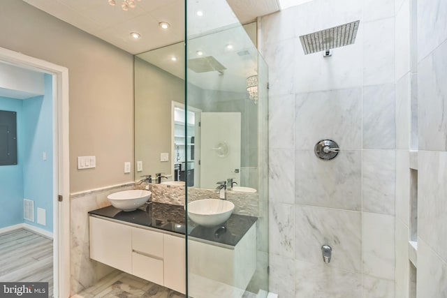 bathroom featuring vanity, hardwood / wood-style floors, a tile shower, and electric panel