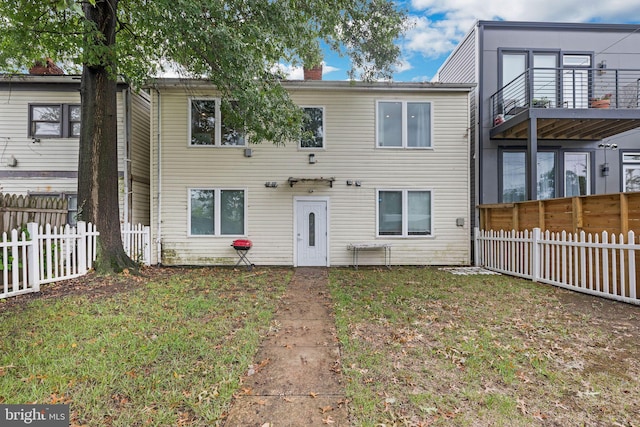 view of front facade featuring a balcony and a front lawn