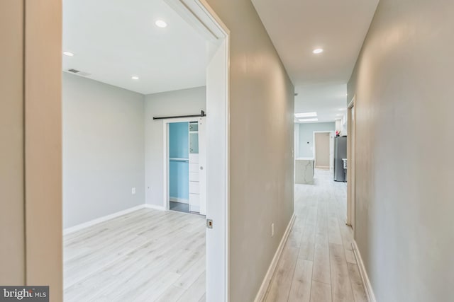 hallway featuring a barn door and light hardwood / wood-style floors