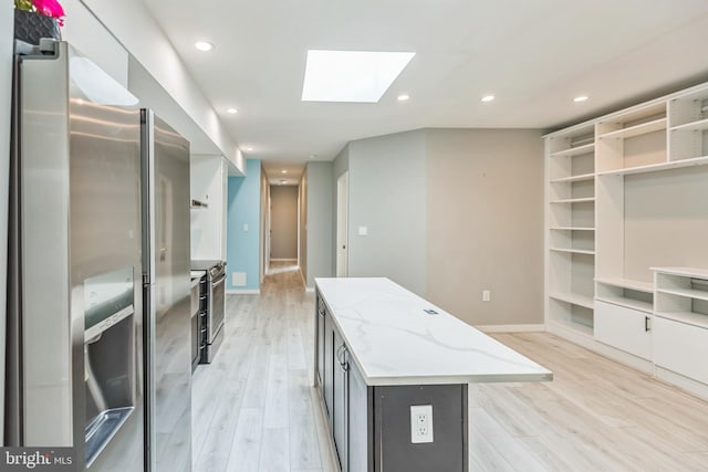 kitchen with light hardwood / wood-style flooring, a center island, a skylight, and appliances with stainless steel finishes