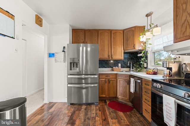 kitchen featuring dark hardwood / wood-style flooring, backsplash, stainless steel appliances, sink, and hanging light fixtures