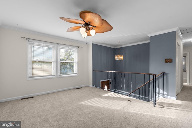 empty room featuring ceiling fan with notable chandelier, crown molding, and carpet flooring