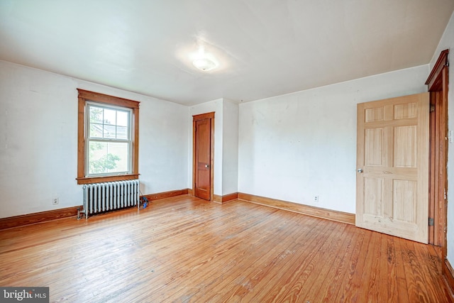 spare room featuring radiator heating unit and light hardwood / wood-style flooring