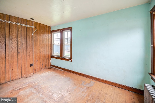 empty room featuring light hardwood / wood-style floors and wood walls