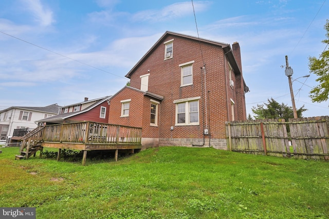 back of property with a yard and a wooden deck