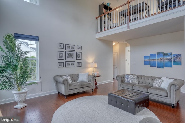 living room featuring a towering ceiling and dark hardwood / wood-style flooring