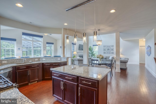 kitchen featuring a kitchen island, dark hardwood / wood-style flooring, light stone counters, and decorative light fixtures