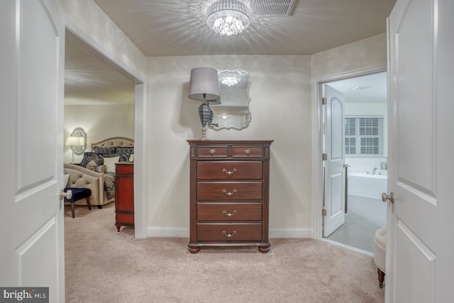 corridor featuring a chandelier and light colored carpet