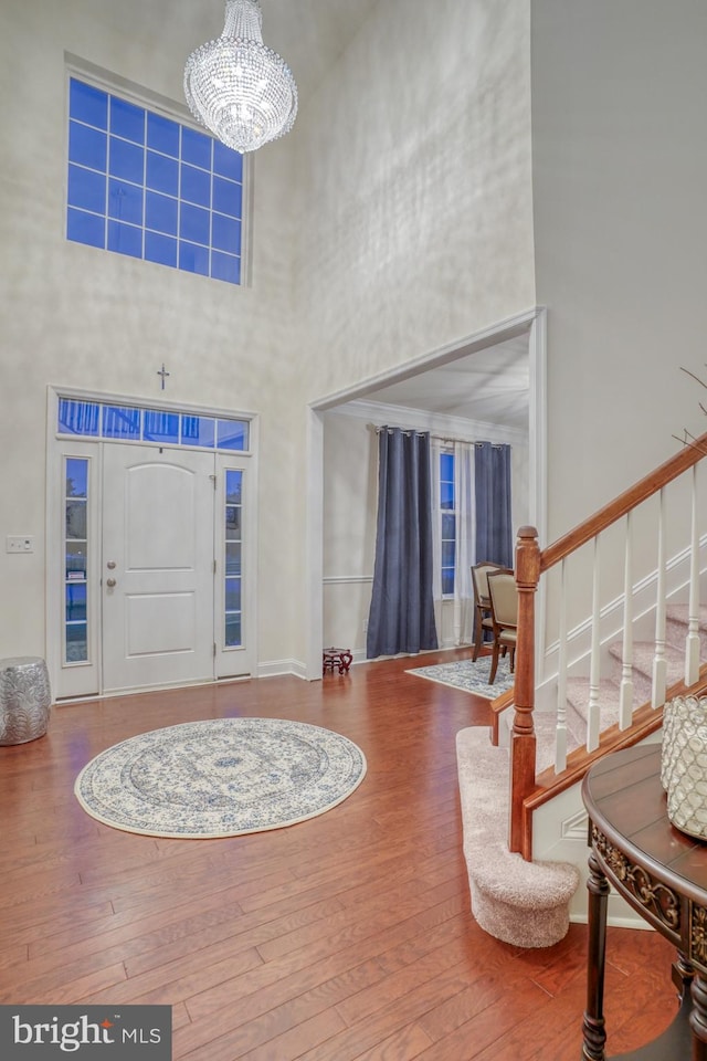 entrance foyer featuring a notable chandelier, hardwood / wood-style flooring, and a high ceiling