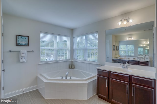 bathroom with tiled tub, vanity, plenty of natural light, and tile patterned flooring