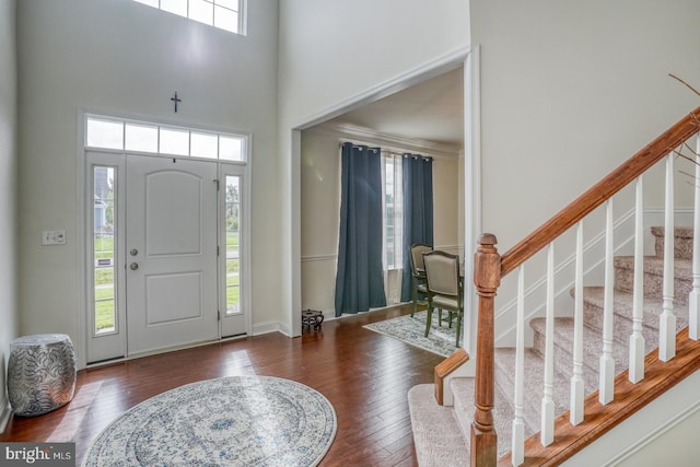 foyer featuring a healthy amount of sunlight, a towering ceiling, and dark hardwood / wood-style floors