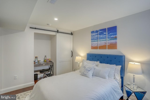 bedroom with a barn door and dark wood-type flooring