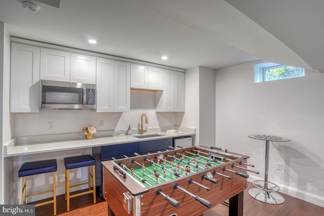 rec room with light hardwood / wood-style floors and sink