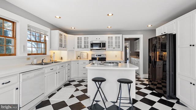 kitchen featuring appliances with stainless steel finishes, white cabinets, sink, and a kitchen bar