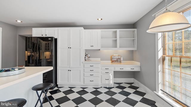 kitchen with white cabinetry, built in desk, decorative light fixtures, and a kitchen breakfast bar