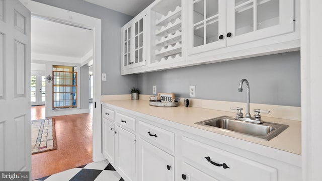 bar with white cabinetry, light hardwood / wood-style flooring, and sink