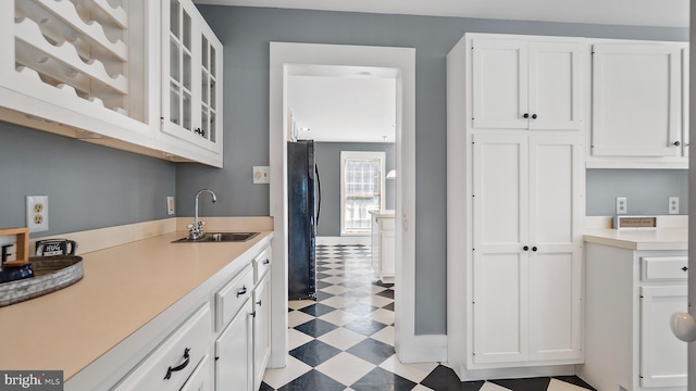 kitchen with sink, white cabinets, and black fridge