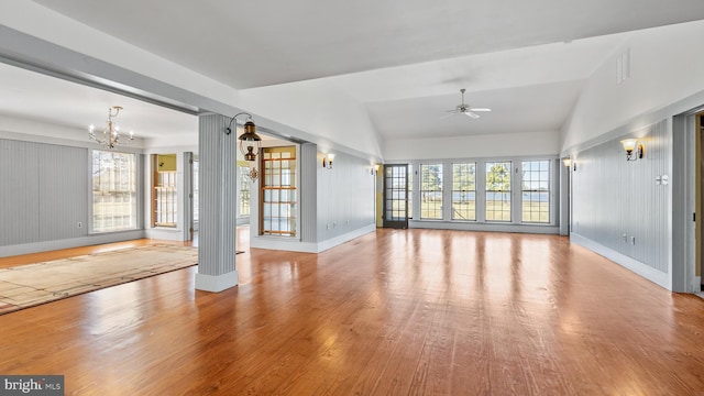 unfurnished living room featuring vaulted ceiling, a healthy amount of sunlight, light hardwood / wood-style flooring, and ceiling fan with notable chandelier