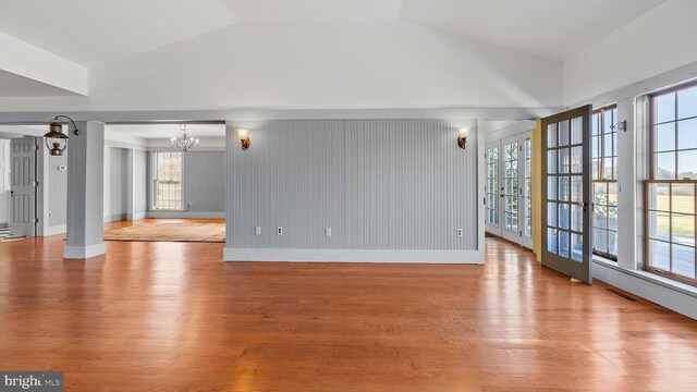 unfurnished living room featuring a healthy amount of sunlight, vaulted ceiling, and light hardwood / wood-style floors