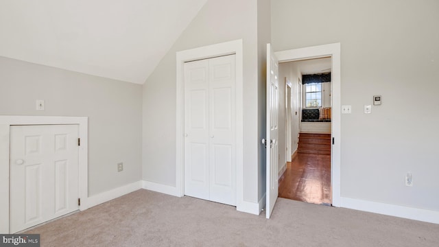 unfurnished bedroom with a closet, light colored carpet, and vaulted ceiling