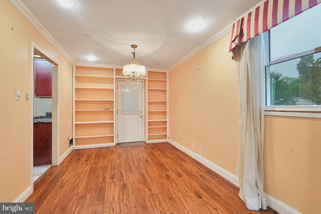 unfurnished dining area with wood-type flooring, a notable chandelier, and ornamental molding