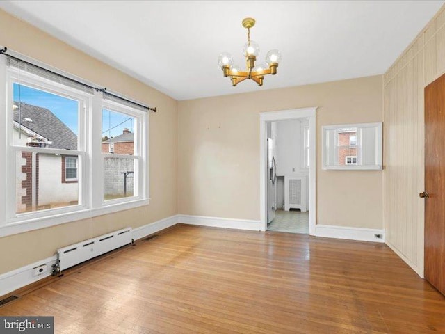 unfurnished room featuring a baseboard radiator, light wood-type flooring, a chandelier, and radiator