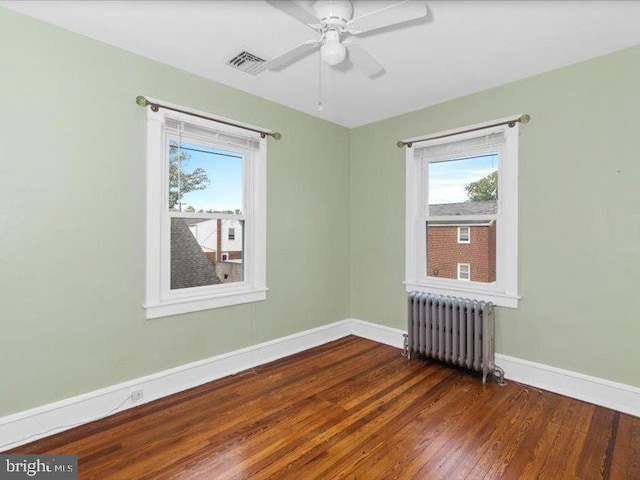 spare room featuring radiator heating unit, ceiling fan, and dark hardwood / wood-style flooring