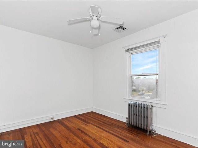 empty room featuring radiator heating unit, ceiling fan, and dark hardwood / wood-style flooring