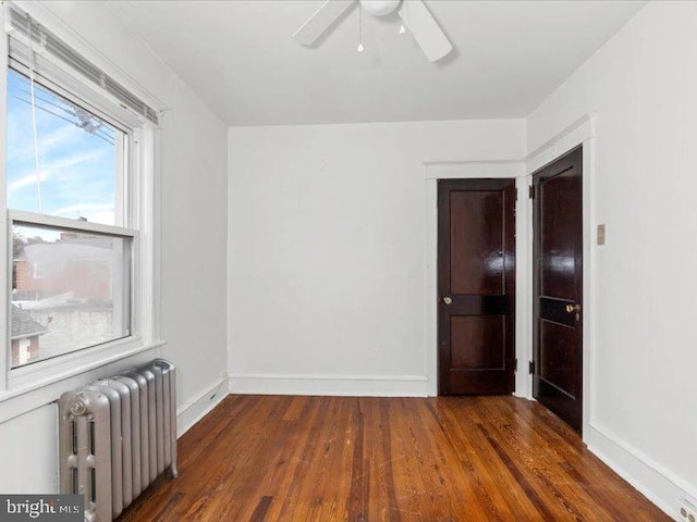 empty room featuring radiator, dark hardwood / wood-style floors, and ceiling fan