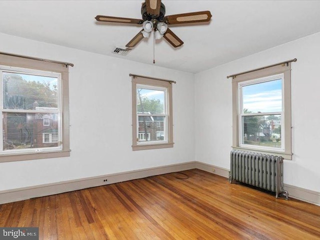 empty room with radiator, ceiling fan, and wood-type flooring