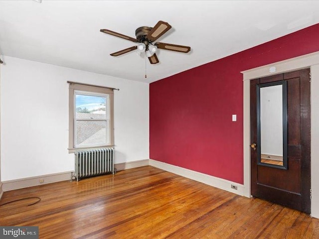 empty room featuring radiator, hardwood / wood-style floors, and ceiling fan