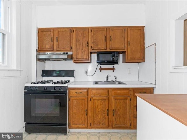 kitchen with wooden walls, black appliances, and sink