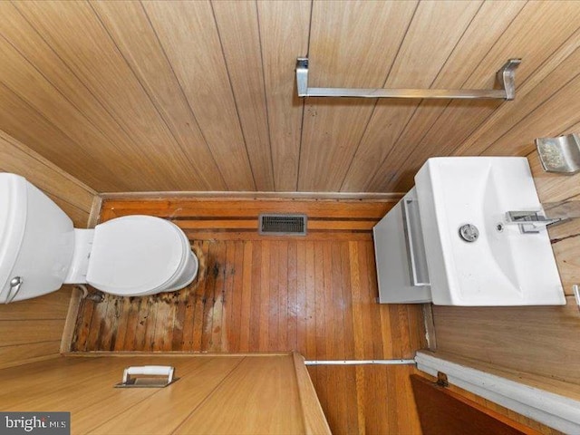 bathroom with wood ceiling, wooden walls, and toilet