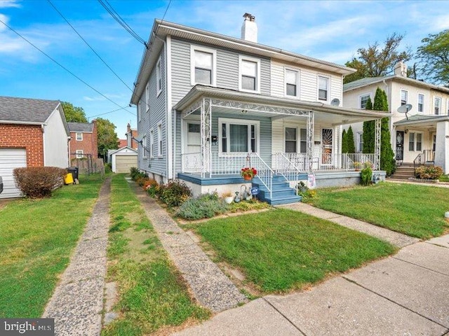 view of front of house featuring a storage unit, covered porch, a front yard, and a garage