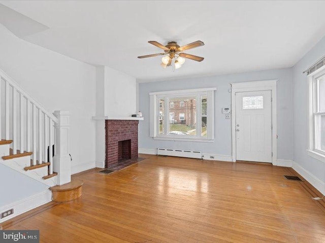 unfurnished living room with light hardwood / wood-style floors, ceiling fan, baseboard heating, and a fireplace